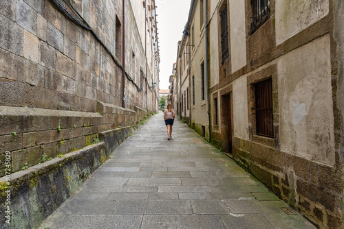 Tourist woman walking through the narrow streets of the historic center of Santiago de Compestela, Galicia.