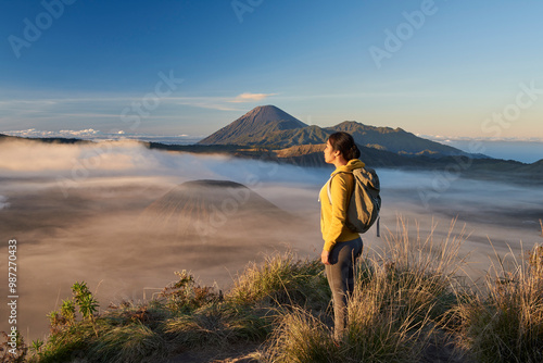Asia, Indonesia, Java, Bromo Semeru national park, mature female tourist trekking at mount Bromo at sunrise, standing at viewpoint admiring view

