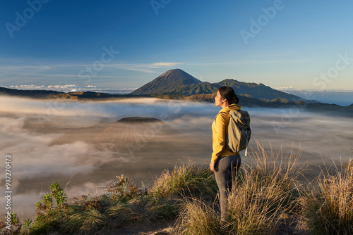 Asia, Indonesia, Java, Bromo Semeru national park, mature female tourist trekking at mount Bromo at sunrise, standing at viewpoint admiring view

