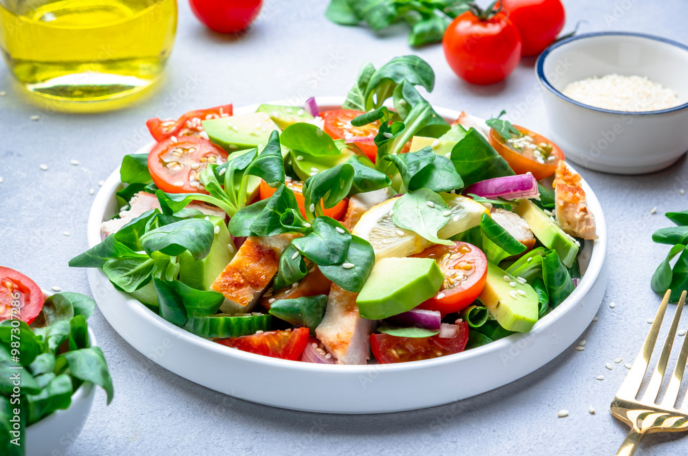 Fresh salad with avocado, chicken, tomatoes and lettuce, gray background, top view Fresh salad with avocado, chicken, tomatoes and lettuce, gray background, top view