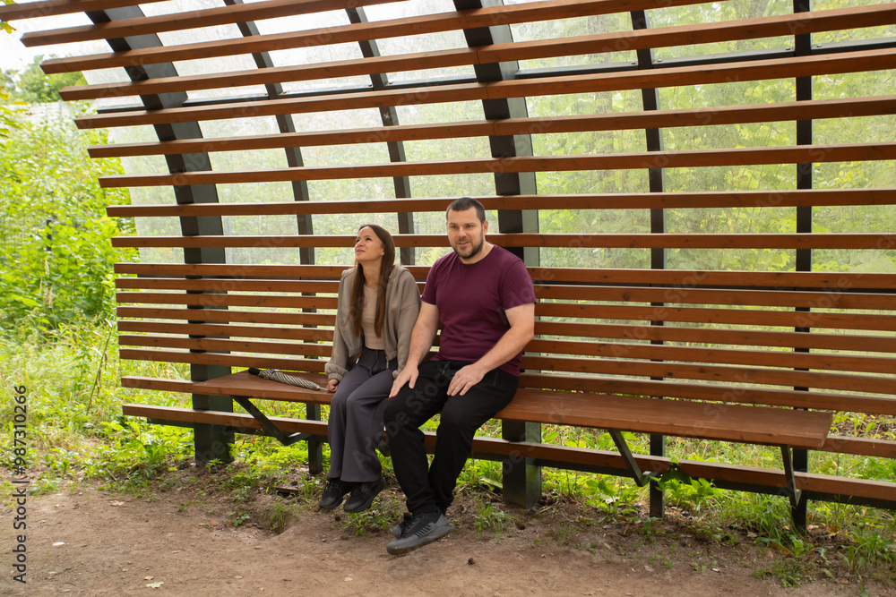 Father and daughter are relaxing in the park, sitting on a bench, family talking about their holiday plans, people enjoying the spring weather, relaxing in nature. Father and daughter are relaxing in the park, sitting on a bench, family talking about their holiday plans, people enjoying the spring weather, relaxing in nature.