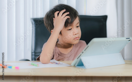  Depressed little boy with tablet,asian child boy learning online on tablet digital at home.