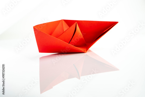 Paper colored boat isolated on white background with reflection. origami crafts. transport concept. origami