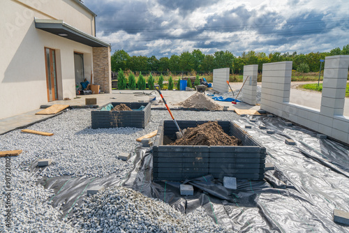 House front garden under construction with flowerpot surrounded by grey pebbles 