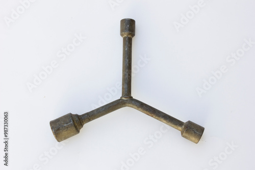 A three-way lug wrench, also known as a tire iron or a cross wrench. This tool is used for loosening and tightening lug nuts on the wheels of vehicles. photo