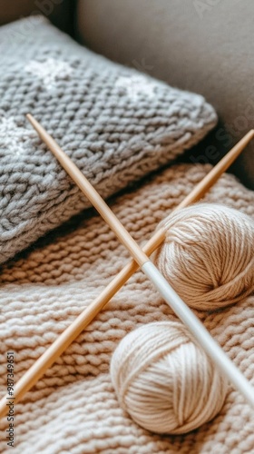 A person sits on a sofa, engaged in knitting with soft gray yarn and needles, surrounded by a pastel pink blanket in a warm, inviting living room