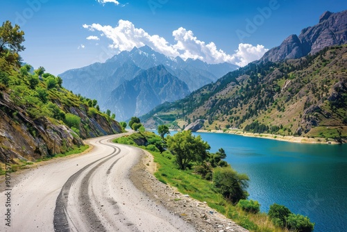 A winding mountain road snaking its way through a lush valley, with a majestic mountain range in the distance and a crystal-clear lake reflecting the blue sky.