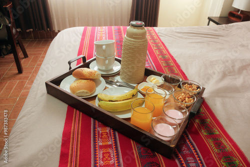 Breakfast in bed room service. closeup of wooden tray on bed, on colourful runner with traditional weave pattern. Healthy wholesome meal provided by hotel hostel stay or guesthouse in Uyuni, Bolivia