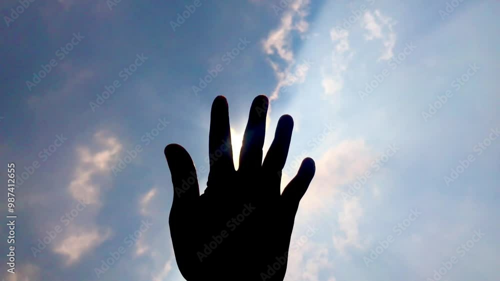 Hands in the sun. Right hand reaching out to sunlight sun silhouette. Right hand and fingers cover sunlight. Man touching sunlight by hand over sky background. Looking at sunlight through his fingers. Hands in the sun. Right hand reaching out to sunlight sun silhouette. Right hand and fingers cover sunlight. Man touching sunlight by hand over sky background. Looking at sunlight through his fingers.