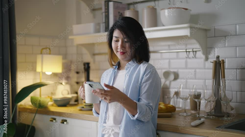 Portrait senior middle aged Women Asian using phone and drinking coffee in kitchen at home. Portrait senior middle aged Women Asian using phone and drinking coffee in kitchen at home.
