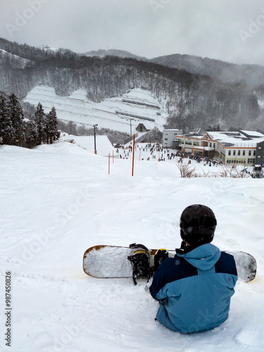 Snowboarder sitting on top of a piste at Yuzawa, Japan photo