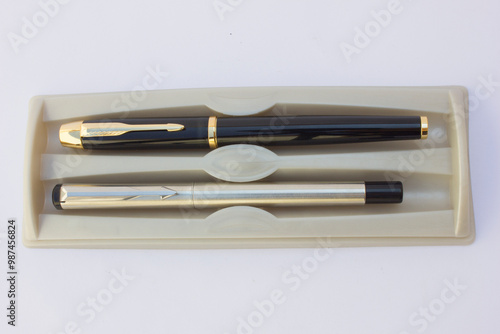 The image showcases two distinct pens. The upper pen boasts a sleek, modern design with a metallic finish and a clip. It appears to be a cap-type pen. 