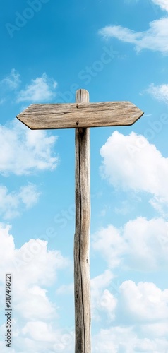 Wooden signpost against a bright blue sky and fluffy clouds, isolated view.