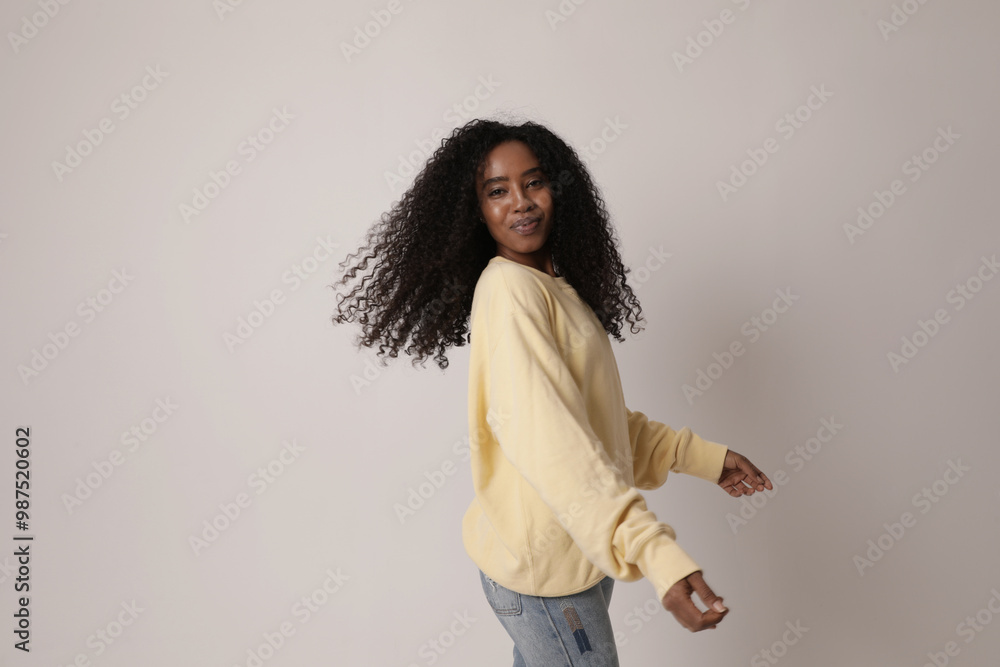Happy teenage girl with dark skin long afro hair poses against white background dressed in casual clothes. 