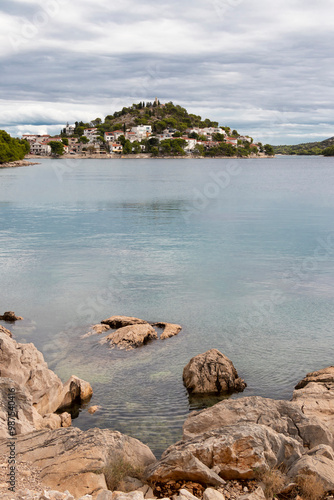 Rocky beach and hill with St Nicholas church in Tribunj, Croatia