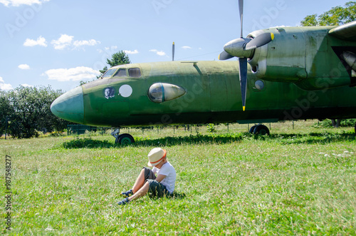 A child stand near an old plane and dreams of becoming a pilot when he grows up. The concept of choosing a future profession.  photo