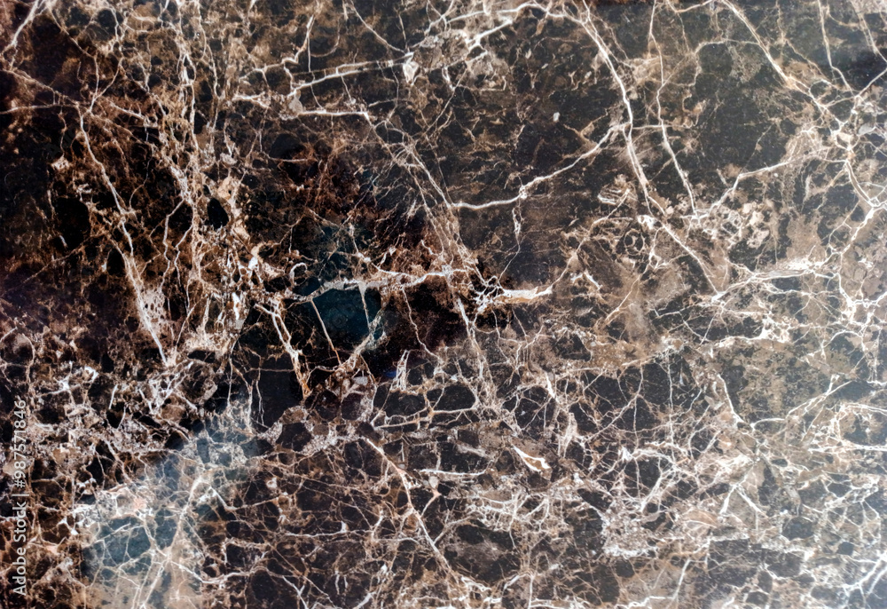 Close-up of a polished dark brown marble surface with intricate white veins and natural patterns, showcasing its rich texture and luxurious design.