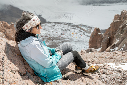 Woman climber sit over Bethlemi hut meteo station and Mount Kazbek base camp.Acclimatization day. Climbing Mount kazbek preparation concept photo