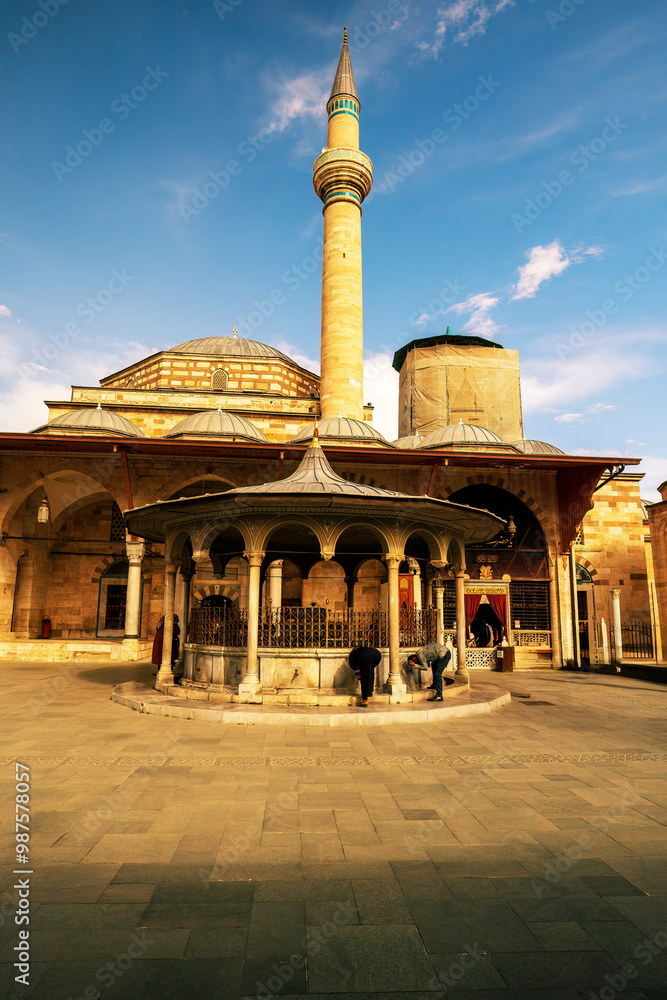 A vibrant view of a historic mosque in Konya, Turkey, showcasing traditional architecture bathed in golden sunlight, with visitors exploring the serene courtyard. Selimiye mosque in konya