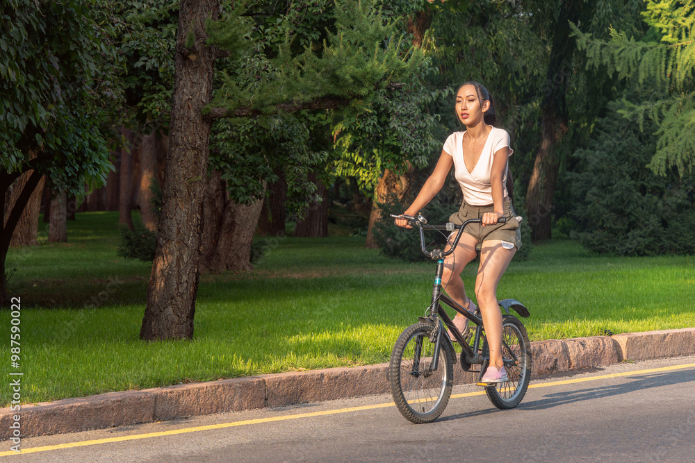 Asian girl rides old bicycle along road in sunset rays. Healthy lifestyle. Asian girl rides old bicycle along road in sunset rays. Healthy lifestyle.
