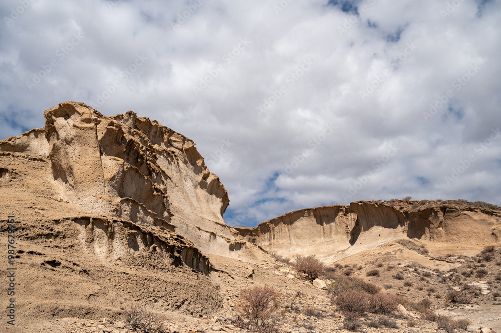 A rocky hillside with a cloudy sky in the background. The sky is mostly blue with some clouds scattered throughout.dng A rocky hillside with a cloudy sky in the background. The sky is mostly blue with some clouds scattered throughout.dng