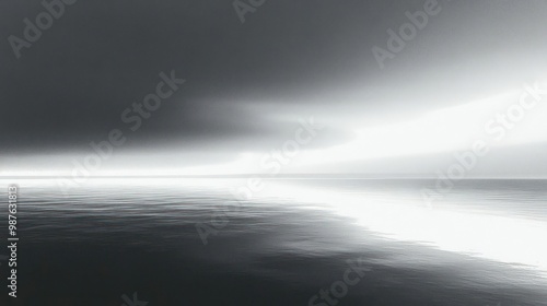 A serene black-and-white seascape with calm waters and dramatic cloud formations.