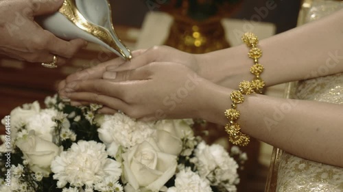 This image captures the delicate hands adorned with beautiful jewelry, set against a backdrop of elegant floral arrangements. The intricate details highlight a moment of grace and cultural significanc photo