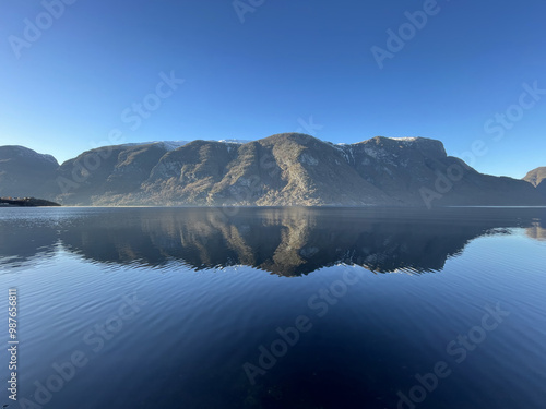 Beautiful cold and blue Fjord in Norway with Reflections of nearby Mountains