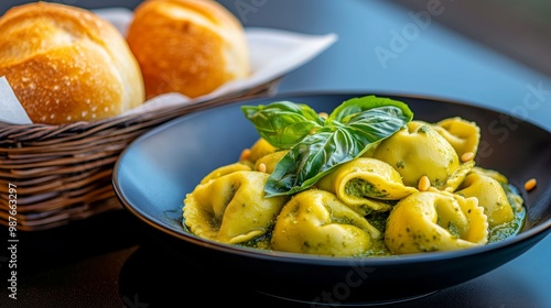 A vibrant plate of pesto tortellini, with fresh basil and toasted pine nuts, arranged next to a basket of freshly baked bread rolls. 