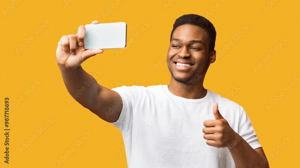 Like. Happy black guy taking selfie and showing thumb up isolated over orange studio background, copyspace, panorama Like. Happy black guy taking selfie and showing thumb up isolated over orange studio background, copyspace, panorama