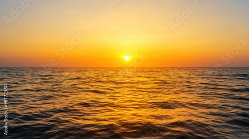 A stunning sunset casts warm golden hues over the calm ocean waves, creating a serene and picturesque seascape.