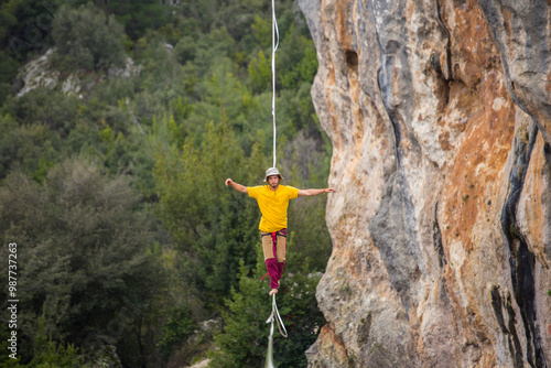 A tightrope walker walks along a cable stretched over a canyon. photo