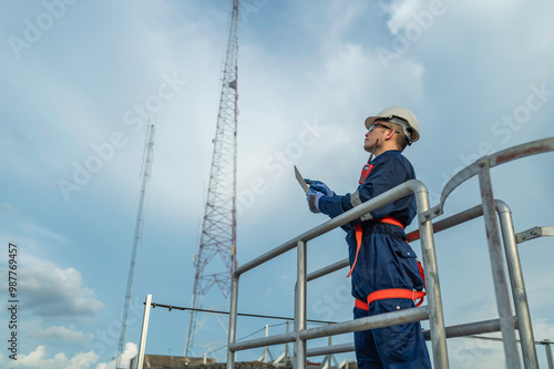 Engineer in Full Safety Gear Climbing a Ladder to Inspect Communication Signals and Industrial Machinery at a High-Risk Transportation Facility