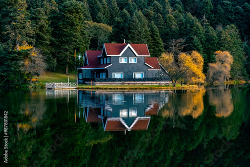 Konstfotografi A distant photo of a wooden lake house on the water in the forest, taken from the opposite angle