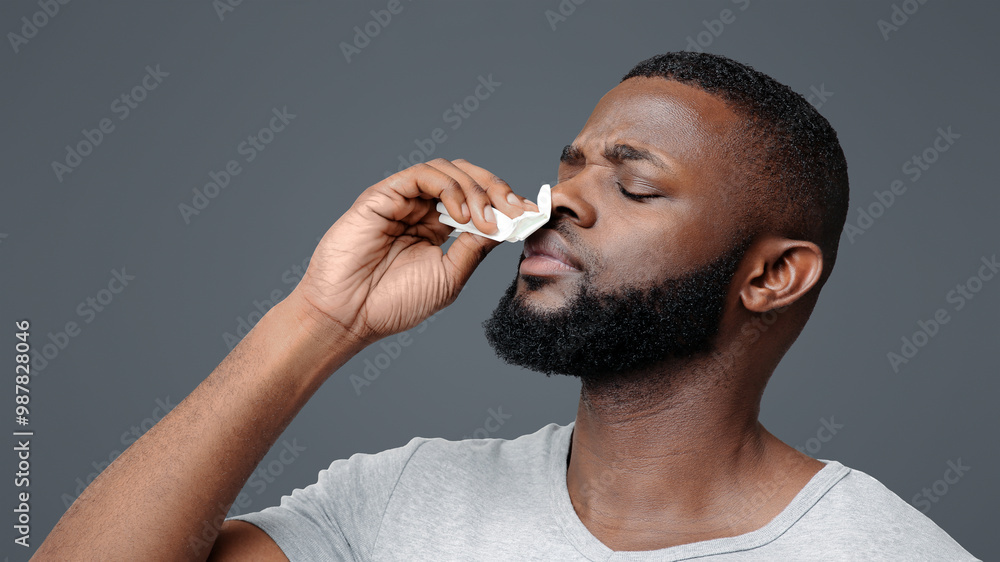 Afro guy touching his nose with napkin, bleeding or having runny nose, free space Afro guy touching his nose with napkin, bleeding or having runny nose, free space