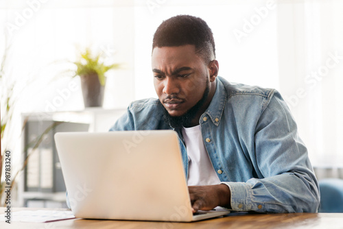 Important task. Focused african american employee working on laptop in office, free space