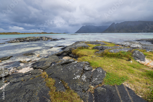 An overcast day in Gimsoy in the Lofoton Islands of Norway. There is a view of the ocean and mountains of this rugged landscape. photo