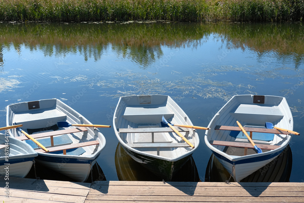Fishing or tourist boats in calm river water. Wooden boats moored at the pier. Fishing or tourist boats in calm river water. Wooden boats moored at the pier.