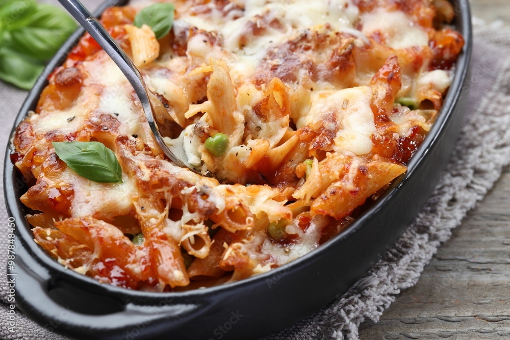 Eating delicious al forno pasta at wooden table, closeup Eating delicious al forno pasta at wooden table, closeup