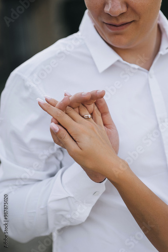 Bride and groom holding hands with fingers crossed. Close-up wedding photo, portrait of happy newlyweds.