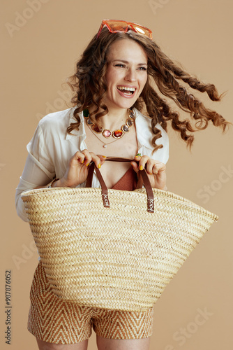smiling trendy female in blouse and shorts against beige