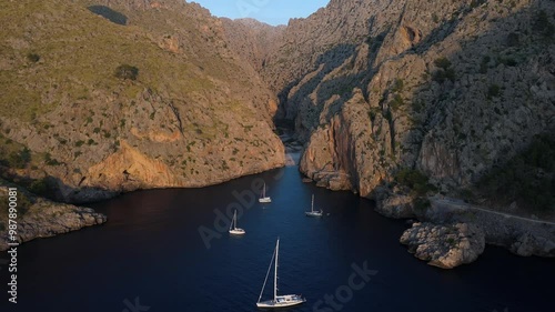 Aerial of yachts in Sa Calobra bay with rocky mountain coast at sunset, Mallorca