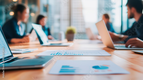 A startup team discussing critical support functions such as IT, finance, and operations in a collaborative meeting. On the table, laptops and documents show financial planning and
