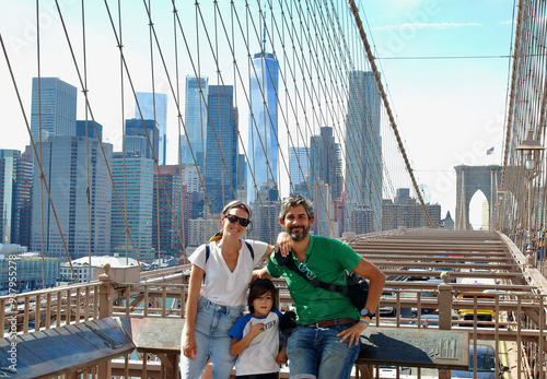 Family of three walking through the amazing Brooklyn bridge in NYC.