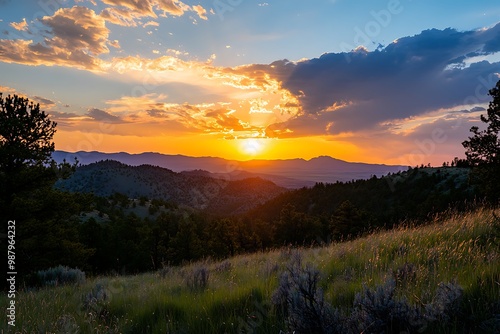 Golden Sunset Over Mountain Range With Cloudy Sky And Green Grass