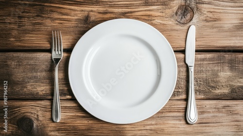 Spoons and forks placed symmetrically on a white plate, sitting on a wooden table with a realistic background for a classic dining setup