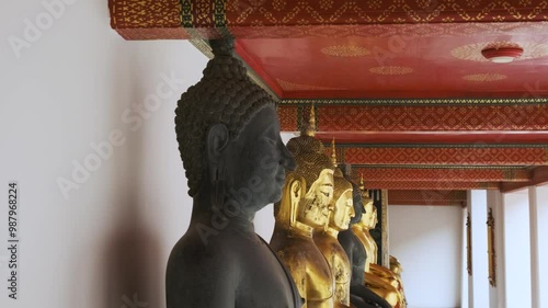 Black Buddha in a row of golden Buddha statues in Wat Pho Temple Complex in Bangkok city, Thailand, Asia. Temple of the Reclining Buddha. Popular travel landmark photo