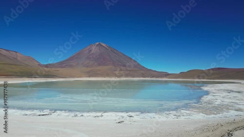 Aerial view of blue salt lake (Laguna Verde) surrounded by volcanoes in the mountains in Bolivia. Drone shot in 4k