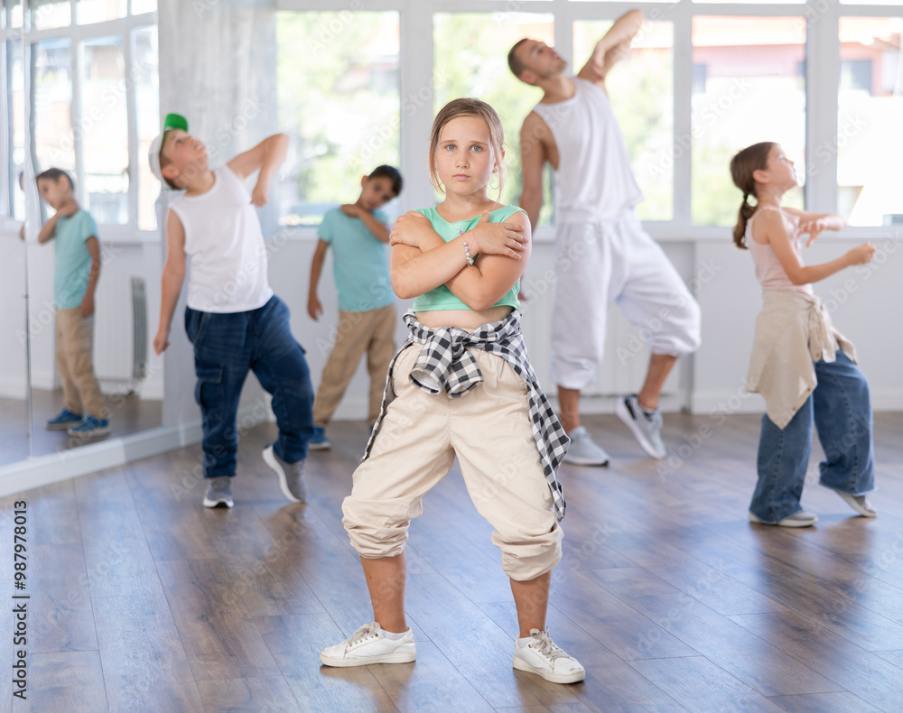 Fototapeta premium Positive cheerful smiling children studying modern style dance in light class indoors with male teacher