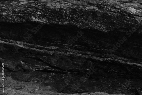 Black and white beach with a huge rock and sea waves. Rock and stone texture